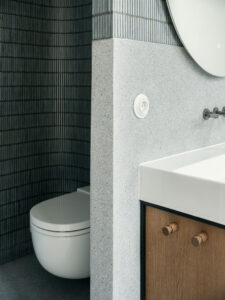 Baño del proyecto SOHO con contraste entre revestimiento cerámico vertical y superficies minerales continuas